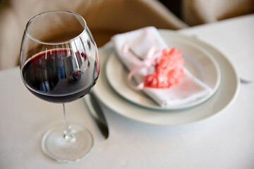Glass of red wine on background of served table in a restaurant. Close-up, selective focus