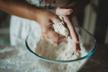 Person molding dough for cookies.Female baker and baking.Person preparing food with flour on wooden round table.Occupation.Fun domestic activity.Mother preparing confectionary.Skill in bakery.