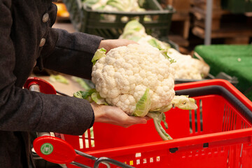 A woman buys cauliflower in a supermarket