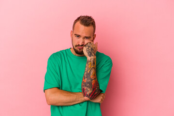 Young caucasian man with tattoos isolated on pink background  who feels sad and pensive, looking at copy space.