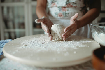 Person molding dough for cookies.Female baker and baking.Person preparing food with flour on wooden round table.Occupation.Fun domestic activity.Mother preparing confectionary.Skill in bakery.