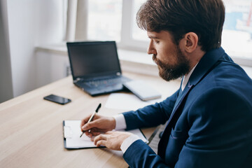 bearded man sitting at a desk in front of a laptop finance official