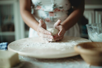 Person molding dough for cookies.Female baker and baking.Person preparing food with flour on wooden round table.Occupation.Fun domestic activity.Mother preparing confectionary.Skill in bakery.