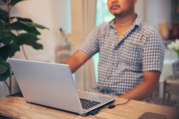 Asian senior man typing on laptop at home office. Serious financial male using computer to work online and wear casual. Technology concept.
