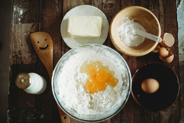 Baking ingredients on wooden table.Healthy homemade recipe for breakfast.Pastry and culinary.Flour and egg yolks in glass bowl.Milk bottle and butter.Home bake space.