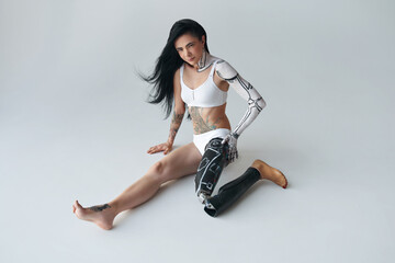 Woman with prothesis leg and cyber body art sitting at the floor and posing at the studio