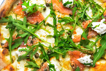 Pizza with mozzarella, salmon slices, fresh arugula. Pizza extreme close up, texture of pizza.