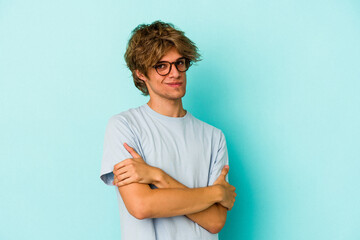 Young caucasian man with make up isolated on blue background  suspicious, uncertain, examining you.