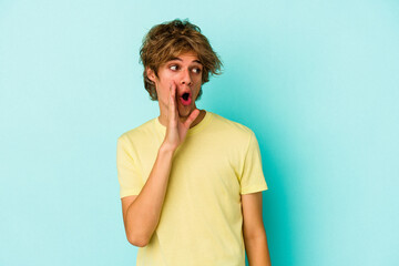 Young caucasian man with make up isolated on blue background  being shocked because of something she has seen.