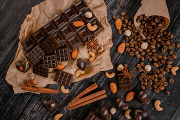 Background with chocolate. Dark organic chocolate with nuts, anise and cinnamon and coffee beans on dark wood background
