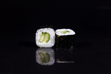 Close-up of delicious sushi rolls on a black glossy Board. Horizontal photo of food on a black background.