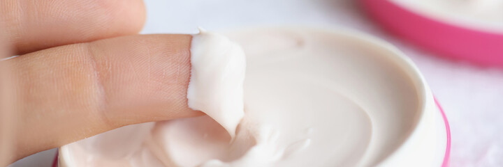 White natural cosmetic cream on fingers closeup