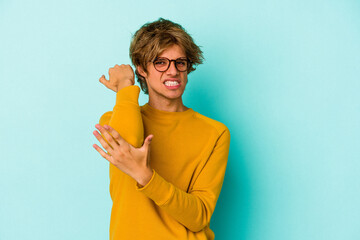 Young caucasian man with make up isolated on blue background  having a neck pain due to stress, massaging and touching it with hand.