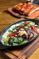 Meat with vegetables served with sauce in a pot over rustic wooden background. Rustic style dinner