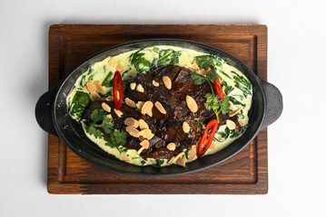 Meat with vegetables served with sauce in a pot over white background. Rustic style dinner