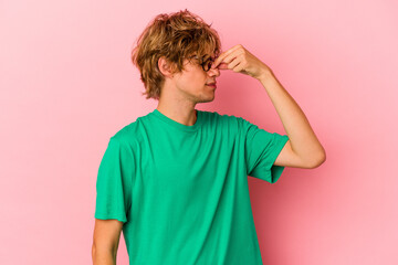 Young caucasian man with make up isolated on pink background having a head ache, touching front of the face. - Powered by Adobe