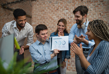 Happy down syndrome man with business colleagues in office, social inclusion and cooperation...