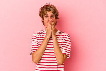 Young caucasian man with make up isolated on pink background shocked covering mouth with hands.