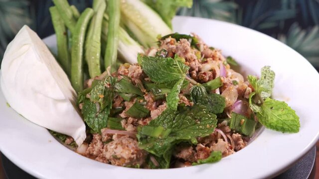 Authentic Thai Larb Moo with Mint and Spices Freshly Cooked Rotating on a White Plate Close Up