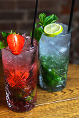 Cocktail collection: Strawberry and classic mojito in glasses over rustic stone background.