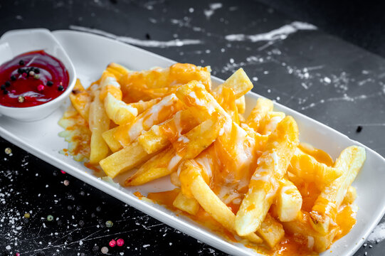 Melted cheese on chips (cheesy chips) served on white place and marble countertop with tomato ketchup