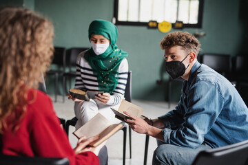 Men and women sitting in circle during group therapy, reading and talking. Coronavirus concept.