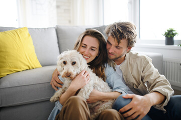 Happy young couple in love with dog indoors at home, resting.