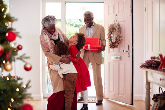 Grandchildren Greeting Grandparents As They Arrive With Presents To Celebrate Christmas