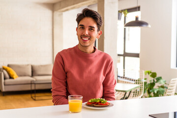 Fototapeta na wymiar Young mixed race man having breakfast in his kitchen happy, smiling and cheerful.