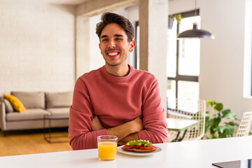 Fototapeta na wymiar Young mixed race man having breakfast in his kitchen laughing and having fun.