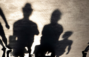 Blurry shadow silhouette of people walking on a promenade on a summer day
