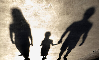 Blurry shadow silhouette of a family walking on a promenade on a summer day