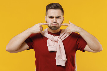 Young fun man 20s in red t-shirt point index fingers on blowing puffing cheeks with funny face mouth inflated with air crazy expression isolated on plain yellow color wall background studio portrait - obrazy, fototapety, plakaty