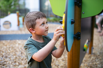 Small happy nursery school boy playing outdoors on playground.