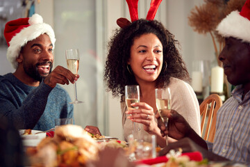 Multi Generation Family In Paper Hats Enjoying Eating Christmas Meal At Home Together