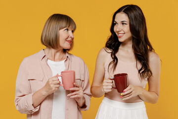 Two young smiling happy daughter mother together couple women in casual clothes look to each other...
