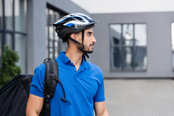 Side view of arabian courier in protective helmet with backpack outdoors