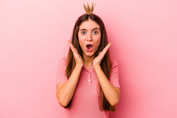 Obraz na płótnie Canvas Young caucasian woman wearing crown isolated on pink background surprised and shocked.