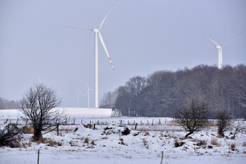 snow falling on the space of meadows and forest before wind turbinesrest
