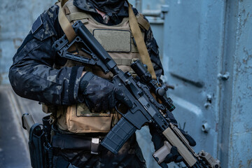 modern soldier in black multicam uniform with rifle, urban background  - 455270470