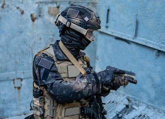 Fototapeta premium modern soldier in black multicam uniform with rifle, urban background 