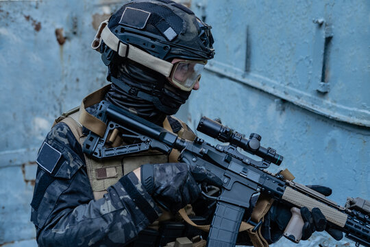 modern soldier in black multicam uniform with rifle, urban background 