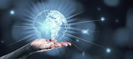 Hand holding glowing globe hologram on blue bokeh background. Digital interface and global innovation.