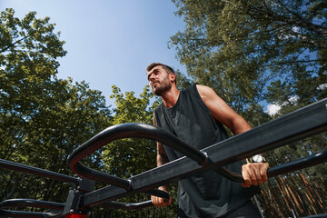 Calm strong guy working out on sportsground