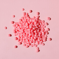 Beautiful pink depilation hot wax granules on pink background. Depilatory wax. Epilation, depilation, unwanted hair removal. Top view. - obrazy, fototapety, plakaty
