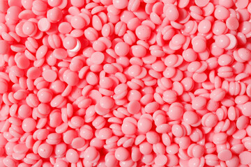 Beautiful pink depilation hot wax granules. Background texture of pink depilatory wax. Epilation, depilation, unwanted hair removal. Top view. - obrazy, fototapety, plakaty