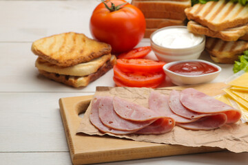 Sandwich. Ingredients for making sandwiches on a board of bread, ham, cheese, tomato on a white background