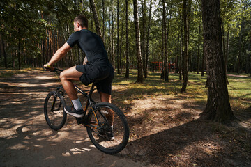 Athletic young man going cycling in forest
