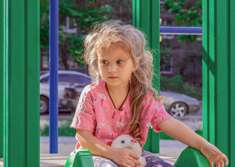 portrait of a child, a charming girl 4-5 years old with long wavy hair, big eyes sits with a...