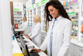 Young female pharmacist working at pharmacy behind the counter.
